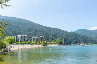 a beach with people on the shore of a lake at RiversTail Retreat Pet-Friendly and Steps to The Lake in Harrison Hot Springs