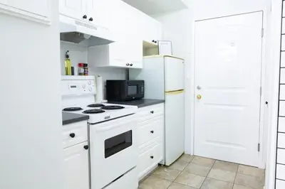 a white kitchen with a stove and a refrigerator at The Backyard at Cedar Springs Walk to Lake and Hot Springs in Harrison Hot Springs