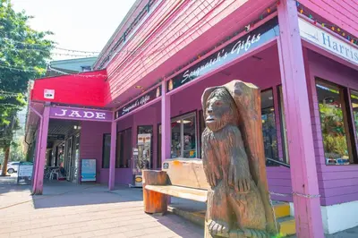 a wooden bench in front of a purple building at Beachy 2 Bed Studio Suite, Balcony and 4 Min to Lake in Harrison Hot Springs