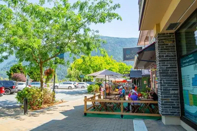 a group of people sitting at a table on a street at Beachy 2 Bed Studio Suite, Balcony and 4 Min to Lake in Harrison Hot Springs