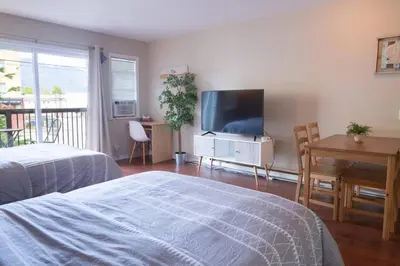 a bedroom with a bed and a flat screen tv at Beachy 2 Bed Studio Suite, Balcony and 4 Min to Lake in Harrison Hot Springs