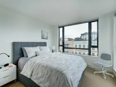 a bedroom with a bed and a chair and a window at Astoria Escape - Bright condo with work desk by Victoria Prime! in Victoria