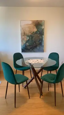 a glass table with four green chairs and a painting at Astoria Escape - Bright condo with work desk by Victoria Prime! in Victoria
