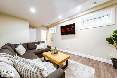 a living room with a couch and a tv on a wall at Sanctuary Suite - KingBed - Wifi - Near WEM - Rogers in Edmonton
