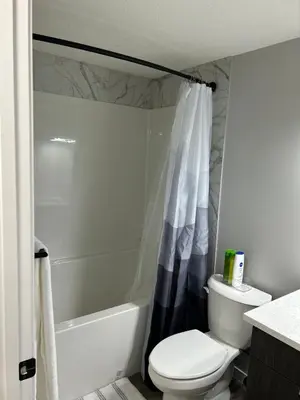 a bathroom with a toilet and a shower curtain at Bright & Spacious 2BR Getaway in Calgary