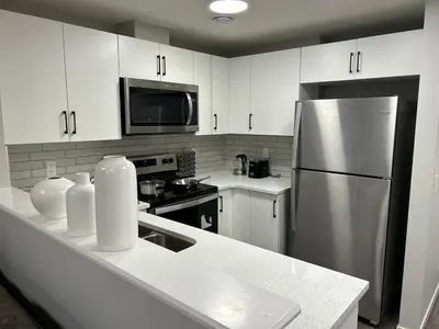 a kitchen with white cabinets and a stainless steel refrigerator at Bright & Spacious 2BR Getaway in Calgary