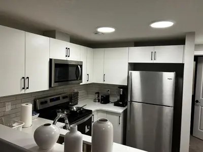 a kitchen with white cabinets and a stainless steel refrigerator at Bright & Spacious 2BR Getaway in Calgary