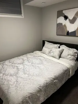 a bedroom with a white bed with a painting on the wall at Bright & Spacious 2BR Getaway in Calgary
