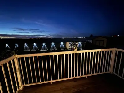 a balcony with a wooden railing at night at Heavenly Cozy Place Inc in Airdrie