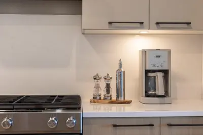 a kitchen counter with a stove and a coffee maker at Sidney Sunnyside - Luxurious Seaside Living in Amazing Sidney by Victoria Prime! in Sidney
