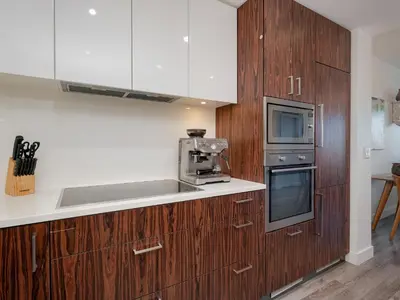 a kitchen with wooden cabinets and a microwave and a stove at Sunset Place-Deluxe One Bedroom Condo in the Escher Building, Sunset Views and Beyond in Victoria