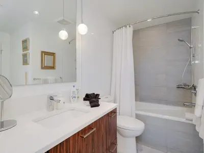 a bathroom with a sink and a toilet and a tub at Sunset Place-Deluxe One Bedroom Condo in the Escher Building, Sunset Views and Beyond in Victoria