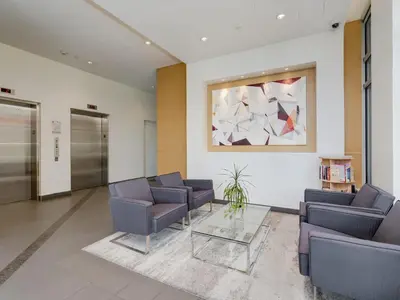 a waiting room with chairs and a table and a painting at Sunset Place-Deluxe One Bedroom Condo in the Escher Building, Sunset Views and Beyond in Victoria