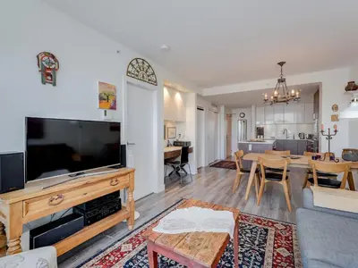 a living room with a large television and a table at Sunset Place-Deluxe One Bedroom Condo in the Escher Building, Sunset Views and Beyond in Victoria