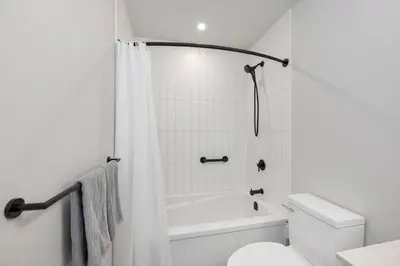 a white bathroom with a toilet and a shower at Whirlaway – Luxurious one bedroom Penthouse with study and 2 parking spots by Victoria Prime! in Victoria