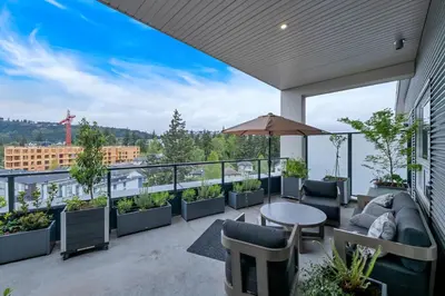 a balcony with a table and chairs and plants at Whirlaway – Luxurious one bedroom Penthouse with study and 2 parking spots by Victoria Prime! in Victoria