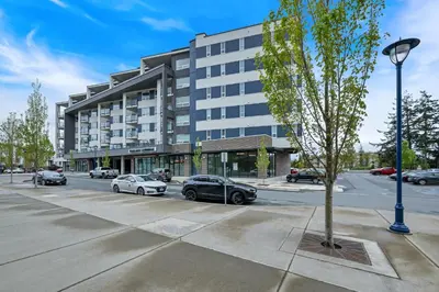 a building with cars parked in a parking lot at Whirlaway – Luxurious one bedroom Penthouse with study and 2 parking spots by Victoria Prime! in Victoria