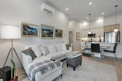 a living room with a white couch and a kitchen at Whirlaway – Luxurious one bedroom Penthouse with study and 2 parking spots by Victoria Prime! in Victoria