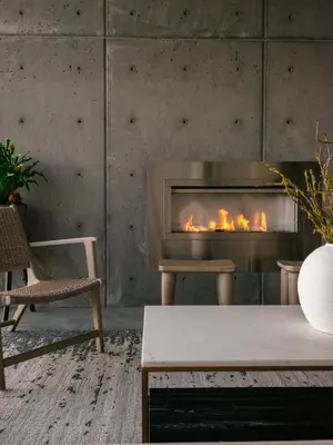 a fireplace in a living room with a table and a chair at Bialto Bed and Breakfast in Penticton