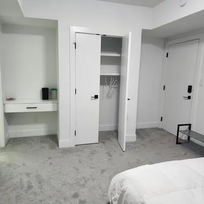 a white bedroom with a bed and a closet at Studio Suite in Northeast, Edmonton in Edmonton