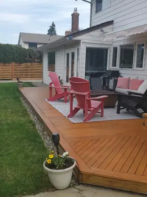 a wooden deck with two red chairs and a table at Just across from the lake ! in Kelowna