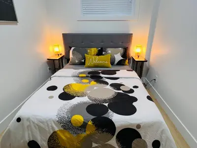 a bedroom with a large bed with yellow and black pillows at New and Modern 1 bedroom suite near beach in Surrey