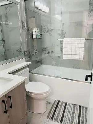 a bathroom with a toilet and a tub and a sink at New and Modern 1 bedroom suite near beach in Surrey