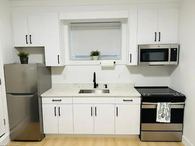 a white kitchen with a sink and a microwave at New and Modern 1 bedroom suite near beach in Surrey