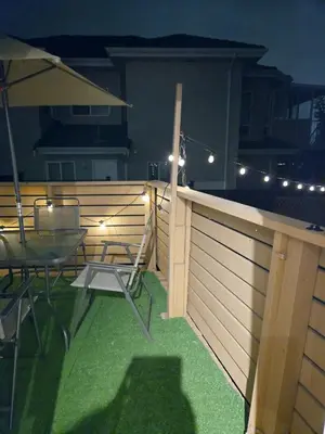 a patio with a fence and a table and an umbrella at Charming Beautiful Private Room With Private Bath and Parking! Near Metrotown in Burnaby