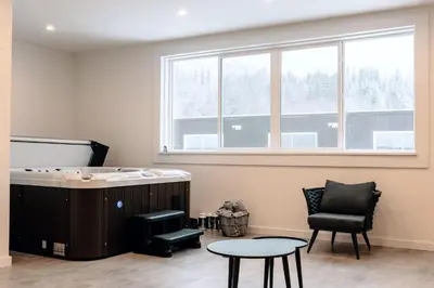 a room with a tub and a chair and a table at Revy To Go - Unique 2-Bedroom Condo in Revelstoke