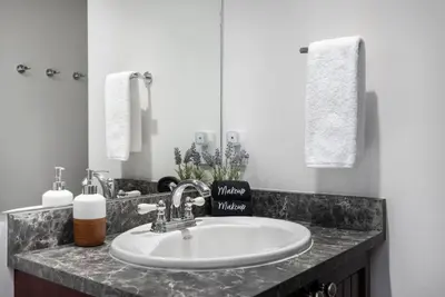 a bathroom with a white sink and a mirror at 1BR plus King Murphy Bed in Tyndall Stone Lodge, Village Location, Pool and Hot Tub, Fireplace in Whistler