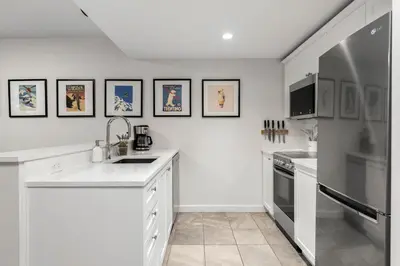 a white kitchen with a sink and a refrigerator at 1BR plus King Murphy Bed in Tyndall Stone Lodge, Village Location, Pool and Hot Tub, Fireplace in Whistler