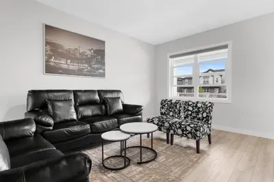 a living room with a black leather couch and a chair at Spacious 3-Bedroom Vacation Home in Calgary with Free Parking in Calgary