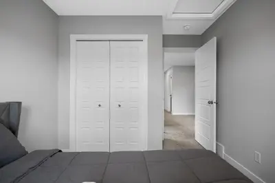 a bedroom with white walls and a bed with white doors at Spacious 3-Bedroom Vacation Home in Calgary with Free Parking in Calgary