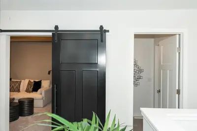 a black barn door in a living room with a couch at Strawberry Fields 4BD Family Movie Room Office in Calgary
