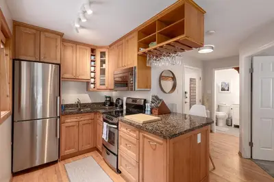 a kitchen with wooden cabinets and a stainless steel refrigerator at 1BR in Powderview, Creekside, Bright and Cozy, Private Ski Storage, Fireplace, Free Parking in Whistler