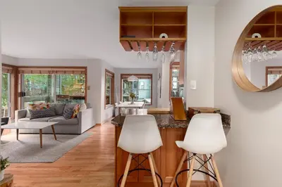 a kitchen and living room with white furniture and a mirror at 1BR in Powderview, Creekside, Bright and Cozy, Private Ski Storage, Fireplace, Free Parking in Whistler