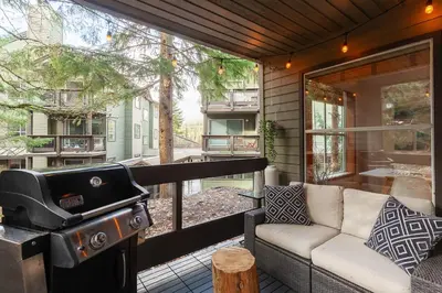 a grill and a couch on a screened in porch at 1BR in Powderview, Creekside, Bright and Cozy, Private Ski Storage, Fireplace, Free Parking in Whistler