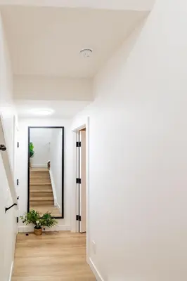 a hallway with white walls and a staircase with a mirror at Free Parking - Beautyrest Beds - Heated Bath Floor in Calgary