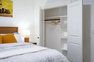 a white bedroom with a bed and a closet at Free Parking - Beautyrest Beds - Heated Bath Floor in Calgary