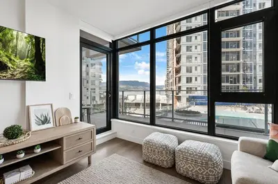 a living room with large windows and a couch at AQUA Corner Unit w Balcony and Amazing View #614 in Kelowna