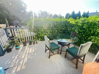 a patio with a glass table and chairs and a hedge at Cozy Nook in Fraser Valley Getaway with Breakfast in Abbotsford