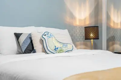 a white bed with a pair of shoes on it at Private Family Entertainer's Suite in Calgary