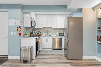 a kitchen with white cabinets and a stainless steel refrigerator at Private Family Entertainer's Suite in Calgary