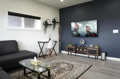 a living room with a couch and a tv on the wall at The Cozy Nook of Seton in Calgary