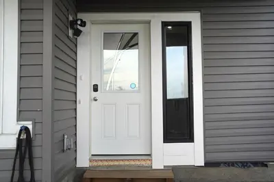 a white door on the side of a house at The Cozy Nook of Seton in Calgary