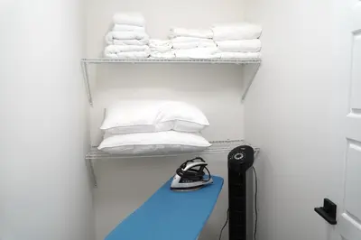 a room with a shelf with towels and a blue bench at The Cozy Nook of Seton in Calgary