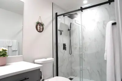 a bathroom with a glass shower with a toilet at The Cozy Nook of Seton in Calgary