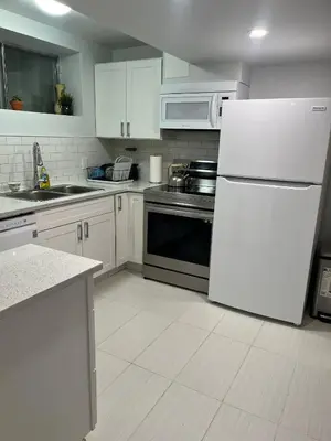 a kitchen with white cabinets and a white refrigerator at Cozy and comfy 1 BEDROOM basement suite at Cougar ridge SW Calgary in Calgary