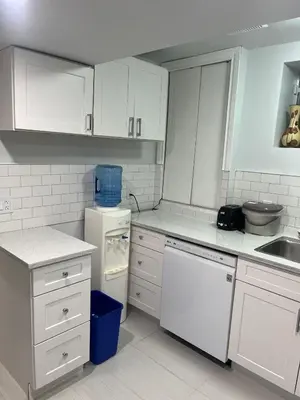 a white kitchen with white cabinets and a sink at Cozy and comfy 1 BEDROOM basement suite at Cougar ridge SW Calgary in Calgary